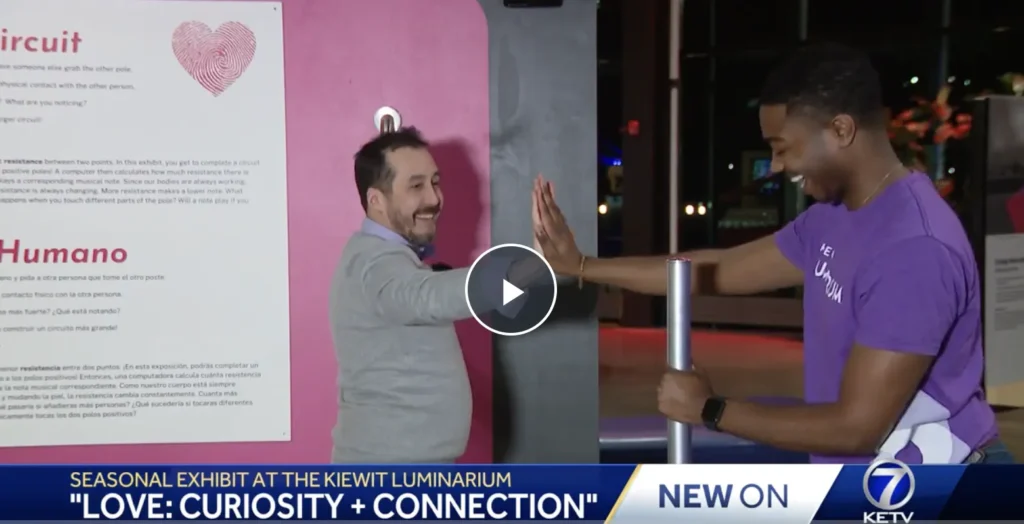 Luminarium Exhibit Technician Justin Alexander and Marketing Coordinator, Quentin Graves demonstrating "Human Circuit" temporary exhibition for Love. Both individuals are smiling.